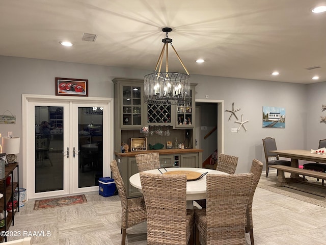 dining area with an inviting chandelier, bar area, and french doors