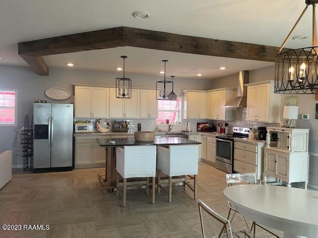 kitchen featuring dark parquet floors, decorative light fixtures, a healthy amount of sunlight, appliances with stainless steel finishes, and wall chimney range hood