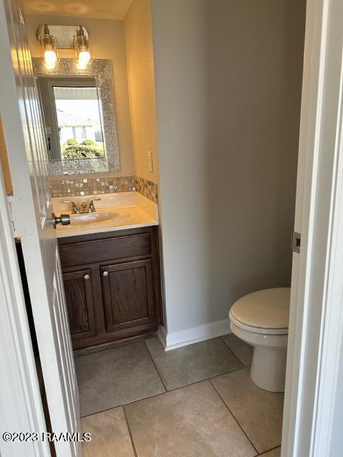 bathroom with toilet, tile flooring, and vanity