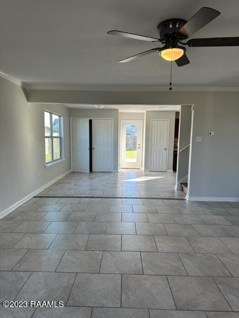 spare room with crown molding, light tile flooring, and ceiling fan