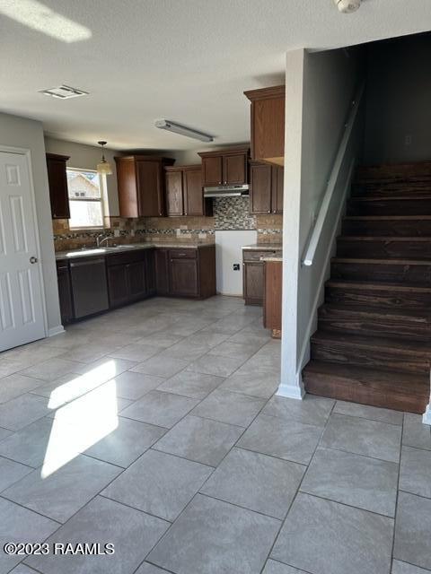 kitchen featuring light tile flooring, pendant lighting, black dishwasher, and tasteful backsplash