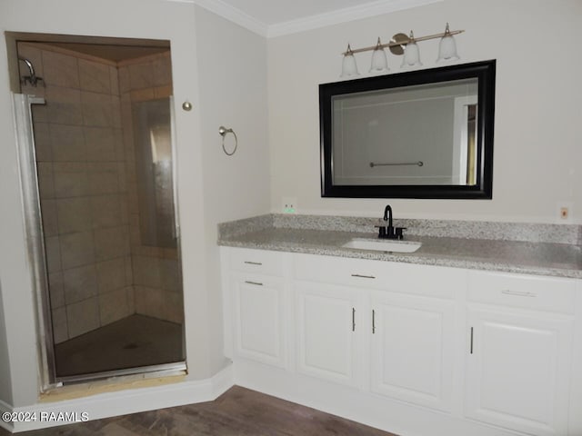 bathroom featuring ornamental molding, vanity, a shower with shower door, and wood-type flooring