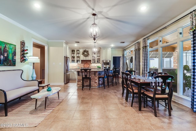 tiled dining space featuring ornamental molding and a chandelier