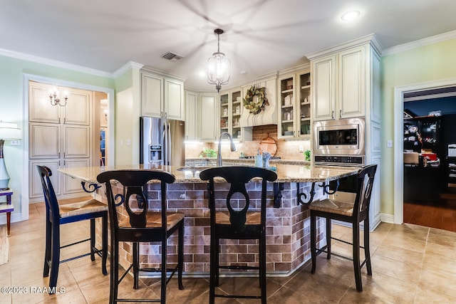 kitchen with appliances with stainless steel finishes, light wood-type flooring, a kitchen bar, and a center island with sink