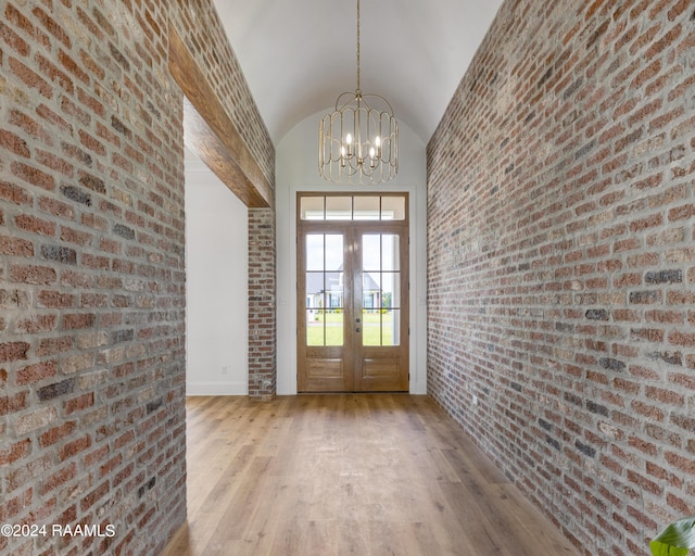 entryway featuring french doors, high vaulted ceiling, an inviting chandelier, and light hardwood / wood-style flooring