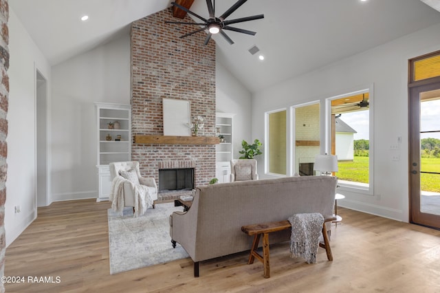 living room with beam ceiling, light wood-type flooring, high vaulted ceiling, and a brick fireplace