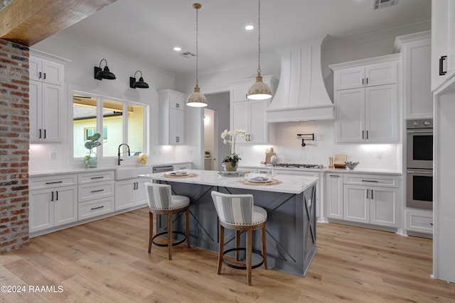 kitchen featuring premium range hood, white cabinetry, a center island, and light hardwood / wood-style floors