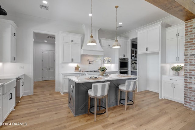 kitchen with white cabinets, decorative light fixtures, light hardwood / wood-style floors, and stainless steel appliances