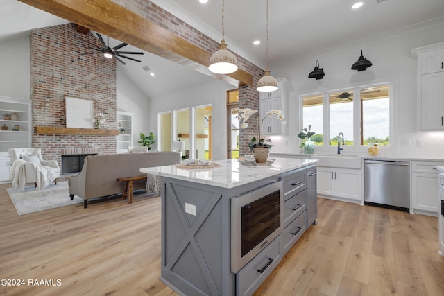 kitchen featuring sink, beamed ceiling, a kitchen island, white cabinetry, and stainless steel appliances