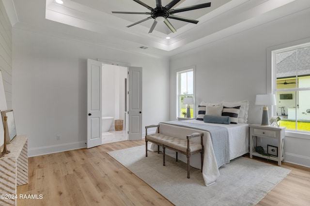 bedroom with a tray ceiling, ceiling fan, crown molding, and light hardwood / wood-style floors