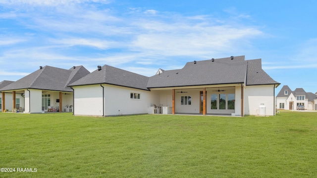 back of property featuring ceiling fan and a yard