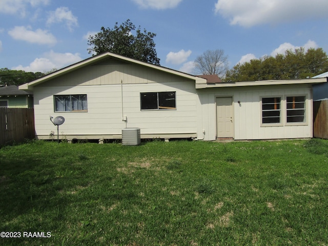 rear view of house featuring central AC and a lawn