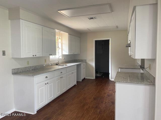 kitchen with dark hardwood / wood-style floors, white cabinets, sink, and light stone countertops