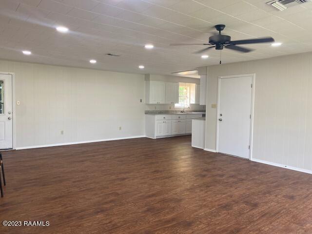 unfurnished living room with ceiling fan, sink, and dark wood-type flooring