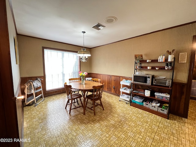 tiled dining room with a chandelier and ornamental molding