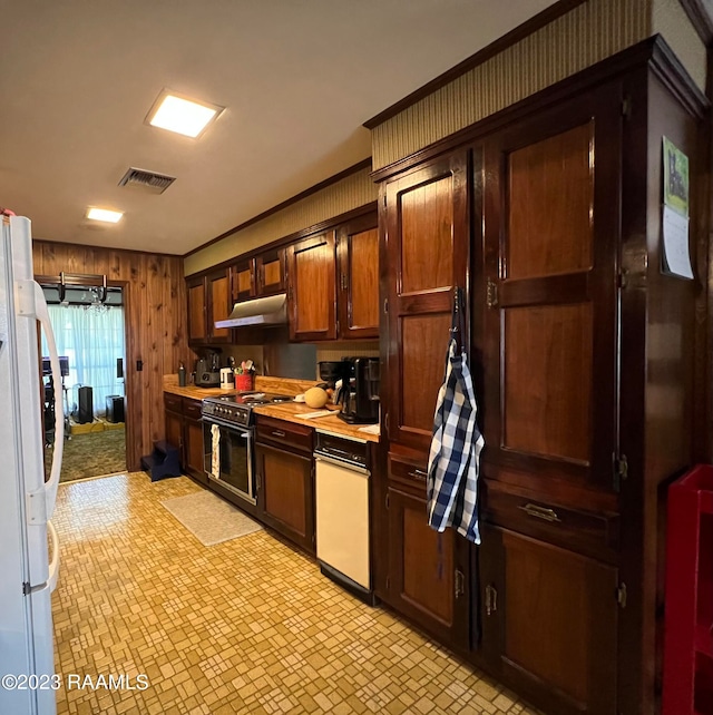 kitchen featuring crown molding, white appliances, wood walls, and light tile floors