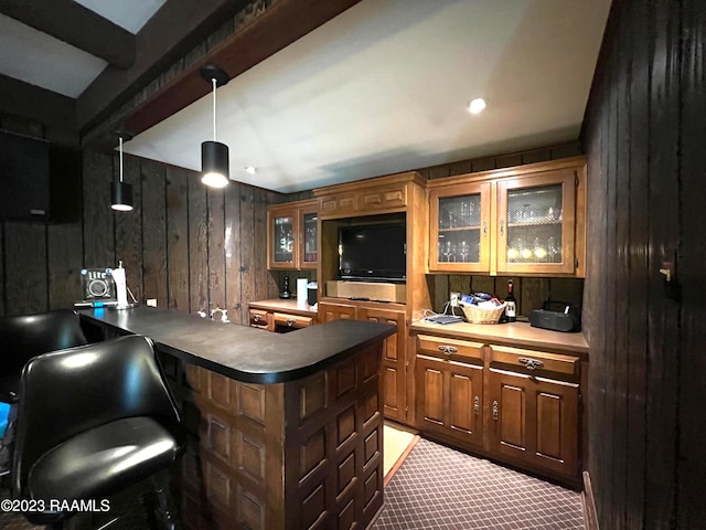 bar with wooden walls, hanging light fixtures, dark carpet, and beam ceiling