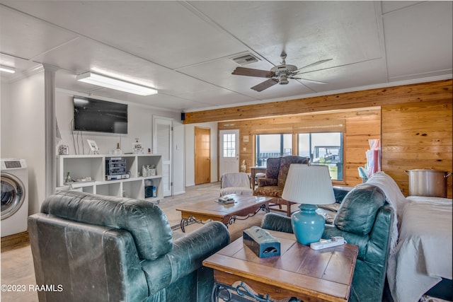 living room with wood walls, washer / dryer, and ceiling fan