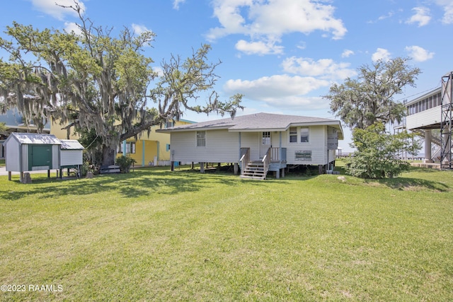 rear view of property with a lawn and a storage unit