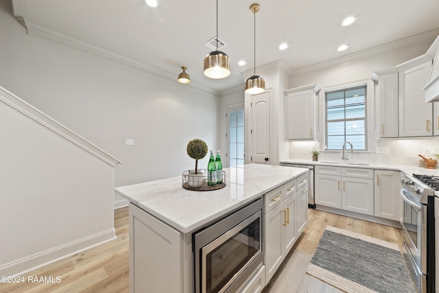 kitchen with light hardwood / wood-style flooring, light stone countertops, appliances with stainless steel finishes, a kitchen island, and white cabinetry