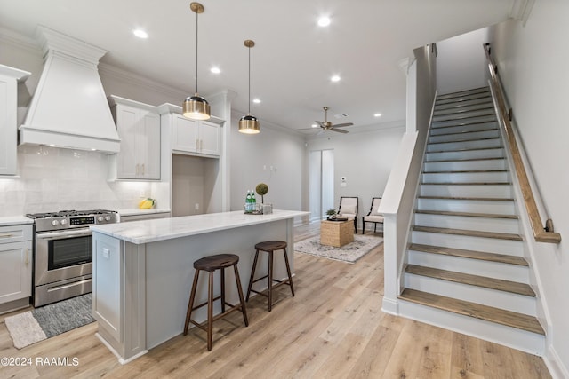 kitchen with a center island, gas stove, hanging light fixtures, and light hardwood / wood-style flooring