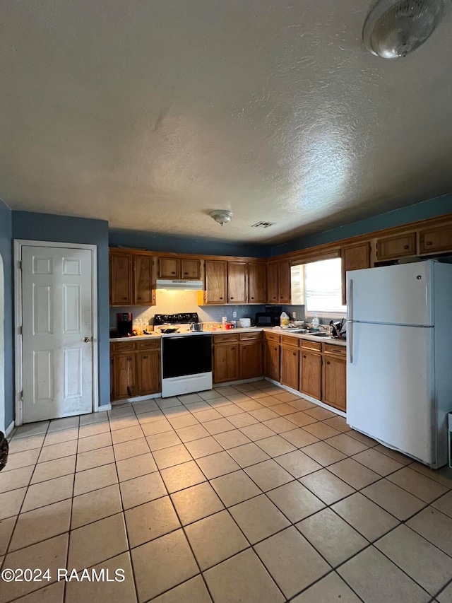 kitchen with a textured ceiling, light tile patterned floors, and white appliances