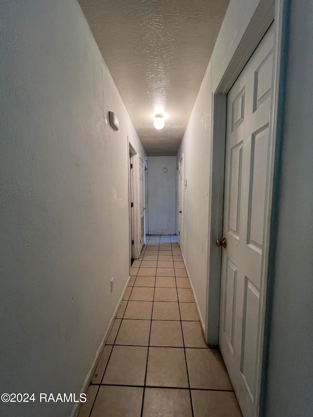 hall featuring a textured ceiling and light tile patterned floors