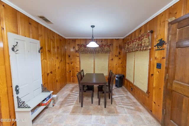 dining space featuring light tile flooring, wooden walls, and crown molding