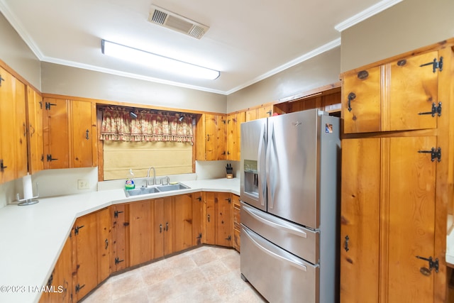 kitchen with crown molding, stainless steel refrigerator with ice dispenser, light tile floors, and sink