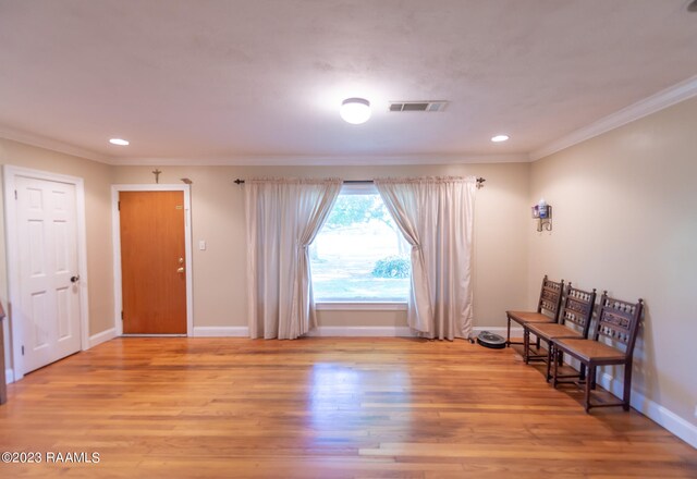 living area with crown molding and light wood-type flooring