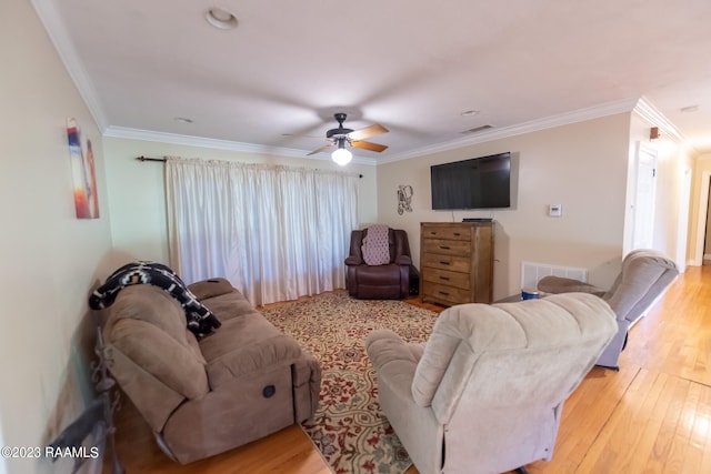 living room with ornamental molding, ceiling fan, and light wood-type flooring