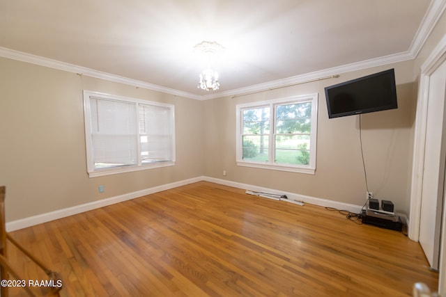 spare room featuring a notable chandelier, light hardwood / wood-style flooring, and ornamental molding