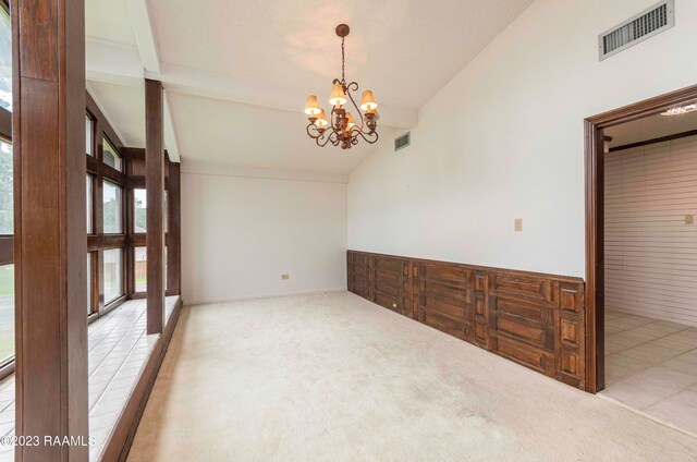 spare room with a chandelier, high vaulted ceiling, and light colored carpet