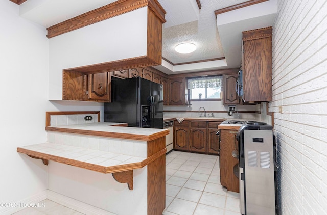 kitchen featuring light tile flooring, black refrigerator with ice dispenser, tile counters, and a textured ceiling