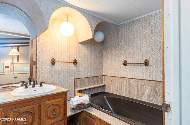 bathroom featuring a bath, vanity, and ornamental molding