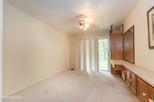 spare room with ceiling fan, crown molding, and light colored carpet