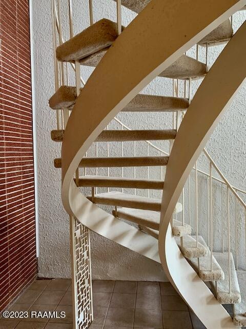 stairway featuring dark tile floors