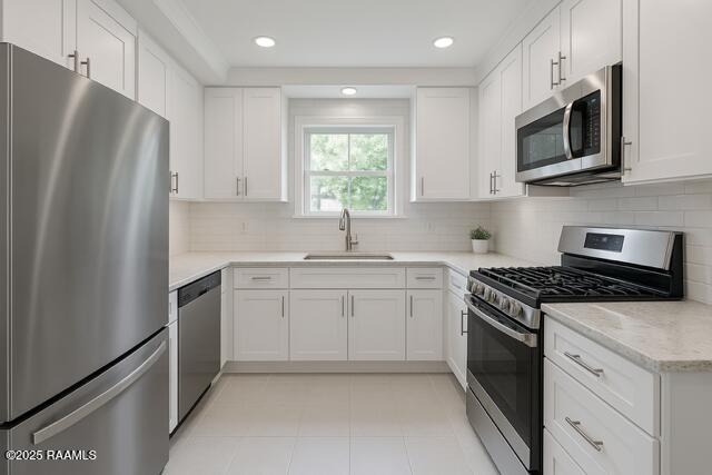 kitchen featuring stainless steel appliances, a sink, white cabinets, tasteful backsplash, and recessed lighting