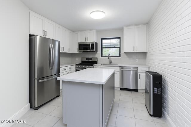 kitchen with stainless steel appliances, a sink, light countertops, a kitchen island, and white cabinets