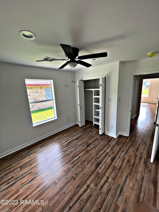 unfurnished bedroom with ceiling fan, a closet, and dark wood-type flooring