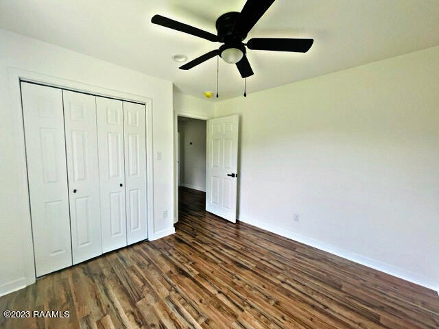 unfurnished bedroom featuring ceiling fan, dark wood-type flooring, and a closet