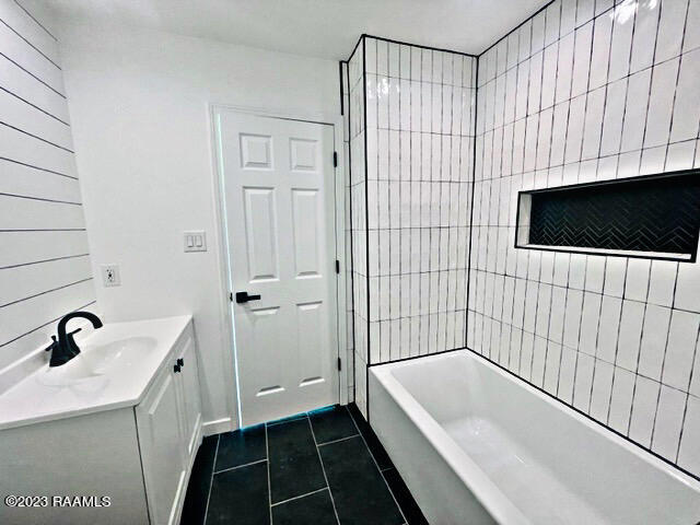 bathroom with tile patterned flooring, vanity, and tiled shower / bath