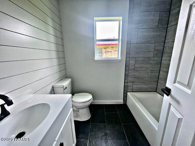 bathroom featuring tile patterned floors, vanity, toilet, and wooden walls