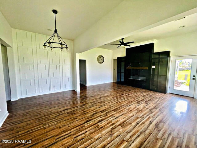 unfurnished living room featuring ceiling fan with notable chandelier and hardwood / wood-style flooring