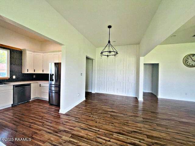 kitchen with appliances with stainless steel finishes, backsplash, white cabinetry, and dark hardwood / wood-style flooring