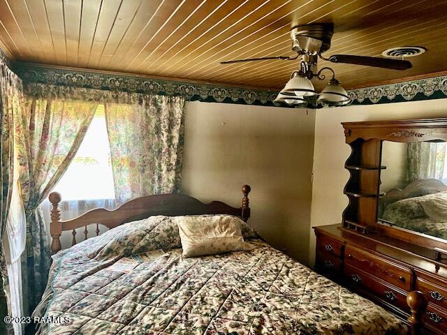 bedroom with wood ceiling and ceiling fan with notable chandelier