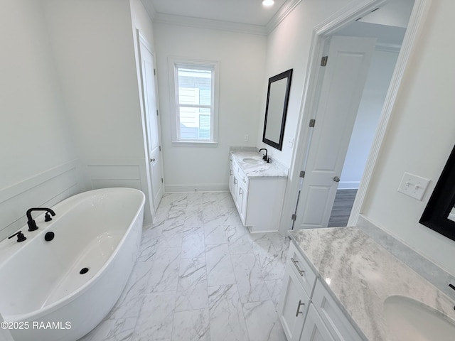 bathroom featuring two vanities, a freestanding tub, ornamental molding, marble finish floor, and a sink