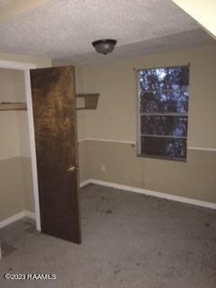 unfurnished bedroom featuring a textured ceiling and dark carpet