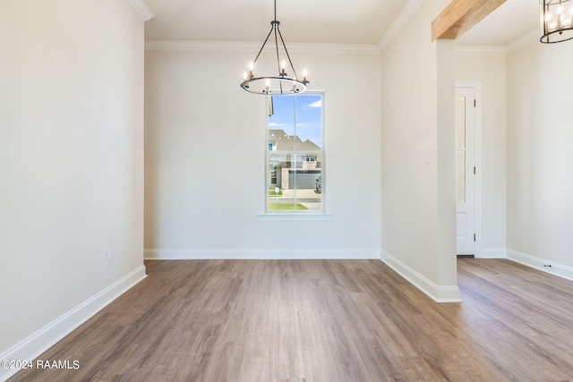 unfurnished dining area featuring baseboards, a notable chandelier, wood finished floors, and crown molding