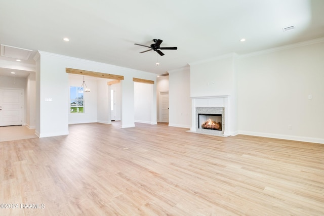 unfurnished living room with baseboards, ceiling fan, attic access, light wood-style flooring, and a fireplace